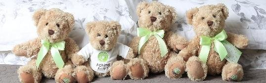 Four teddy bears with green ribbons, one wearing an Aching Arms T-shirt